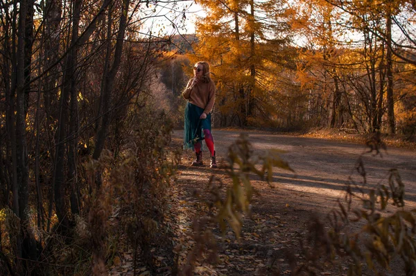 Blondynka idzie ścieżką w jesiennym lesie — Zdjęcie stockowe