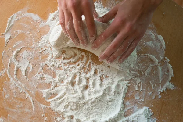 Una ragazza con belle mani scolpisce un impasto per una deliziosa pizza in farina — Foto Stock