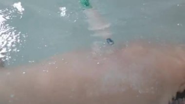 Sıcak maden suyuyla dolu bir küvette kadın ince bacağı. Basınç altında bir hortumdan su akar, kızın kalça masajına neden olur. Yakın plan. Parlak oda.