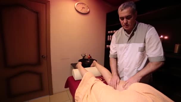 Het meisje ligt op een rode tafel, bedekt met een oranje handdoek. — Stockvideo