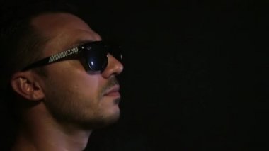 Gözlüklü genç bir adam dudaklarını üzüm çileğiyle alır..