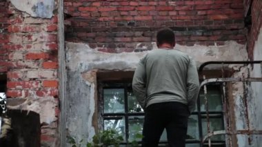 Adamın biri parçalanmış merdivenlerden aşağı iniyor..