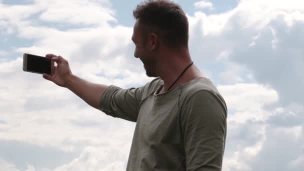 Un joven en el cielo se toma una selfie . — Vídeo de stock