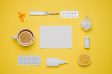 Haplar, tıbbi termometre, burun spreyi ve limon. Sarı arka planda farklı ilaçlar. Soğuk algınlığı ve grip ilaçları. Hastalık kendini tedavi etme konsepti. Düz yatıyordu. Metin için boş alanı olan üst görünüm.