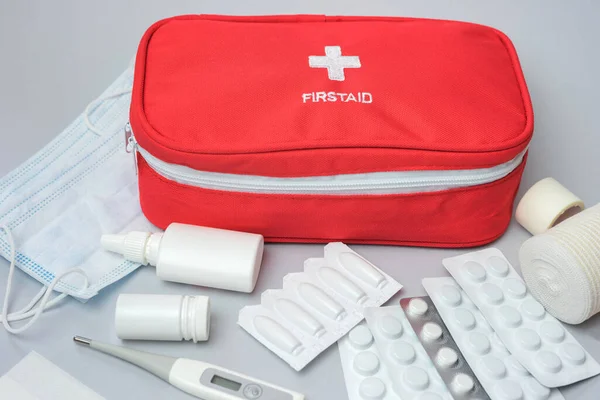 灰色の背景に薬や薬と医療応急処置キット 緊急時のための医療機器や薬と赤い袋 トップ表示 — ストック写真