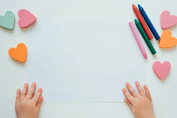 Beyaz kağıt üzerinde bebek elleri. Kalem kalemlerle çizim yapmak. Metin için boş alan. Çocuk sanat konsepti. Ebeveynler için tebrik kartı. Üst manzara, düz uzanma.