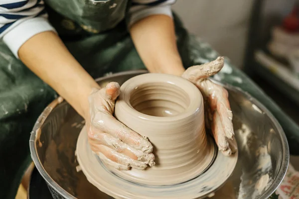 Hands of potter making clay pot on potter\'s wheel. Ceramics and pottery at the workshops.