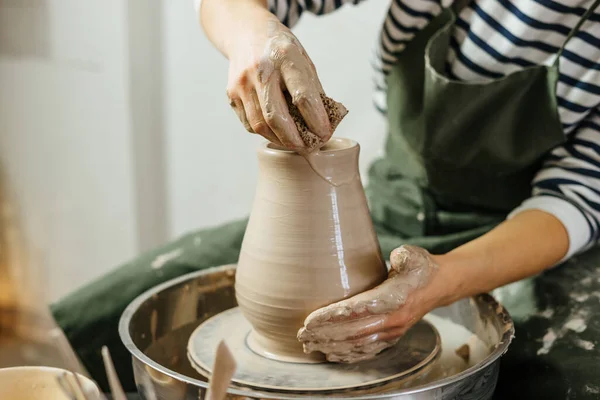 Hands of potter making clay pot on potter's wheel. Ceramics and pottery at the workshops.