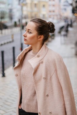 Pembe paltolu şık bir bayan şehirde dikilip poz veriyor.. 