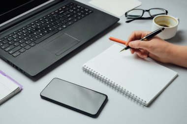 Not defterine yazı yazan ve dizüstü bilgisayarla çalışan kadınların ellerini kapat. Evde Freelancer çalışma alanı ya da ofiste çalışma masası. Ev kavramından çalış.