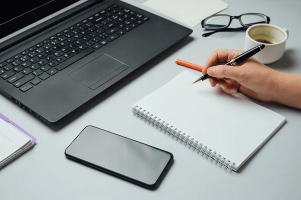 Not defterine yazı yazan ve dizüstü bilgisayarla çalışan kadınların ellerini kapat. Evde Freelancer çalışma alanı ya da ofiste çalışma masası. Ev kavramından çalış.