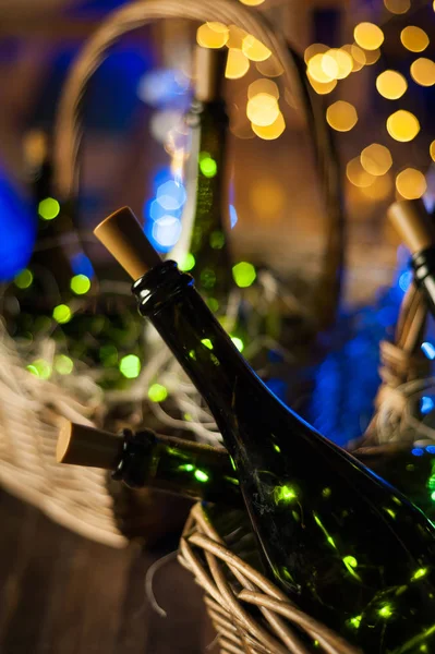 Champagne bottle set with Christmas basket, gold garlands on dar — Stock Photo, Image