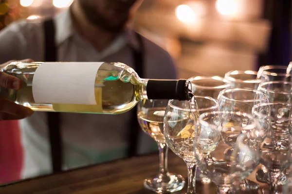 The waiter pours white wine into wine glasses. Close-up on glass — Stock Photo, Image