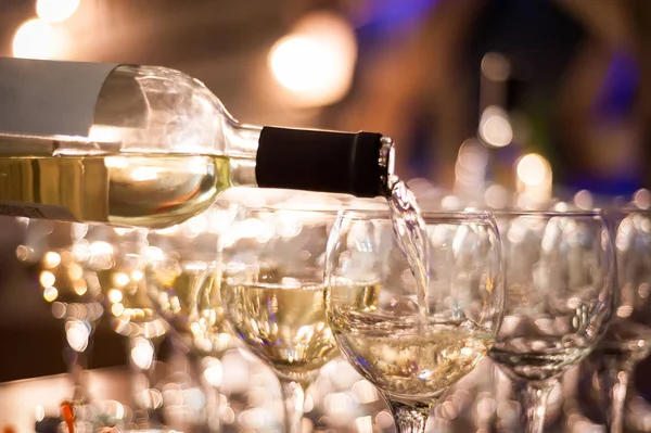 The waiter pours white wine into wine glasses. Close-up on glass — Stock Photo, Image