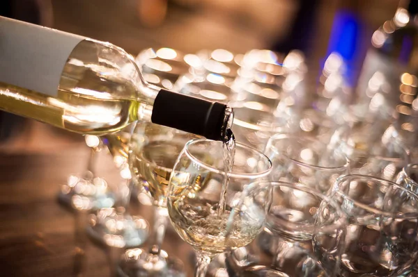 The waiter pours white wine into wine glasses. Close-up on glass — Stock Photo, Image