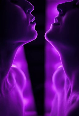 Yüz yüze iki kadının silueti. Parlak lambaların arka planında.