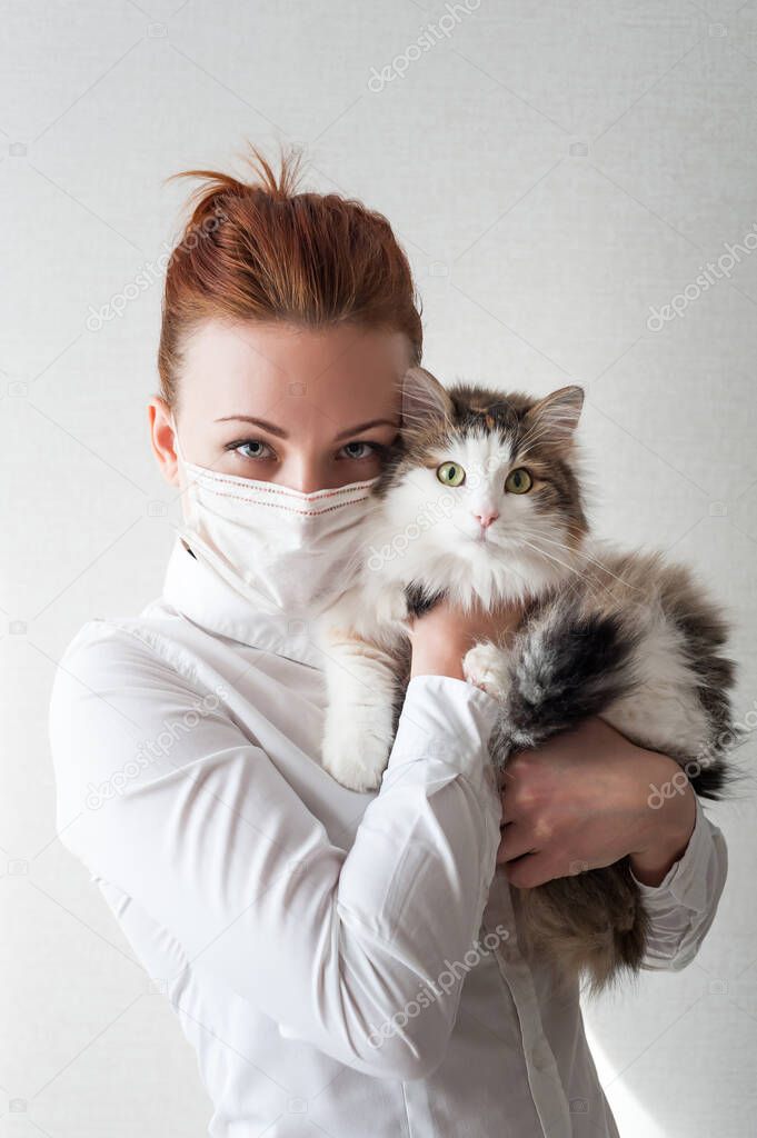 Portrait of a girl in a medical mask. She is holding a pet cat. Close u