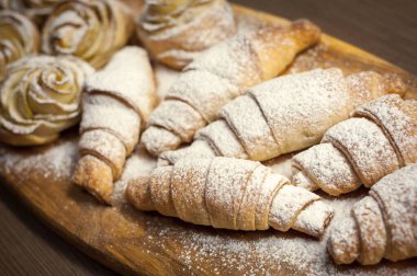 Lezzetli kruvasanlardan ve elmalı pastalardan oluşan bir kafenin ahşap tahtasına yakın.