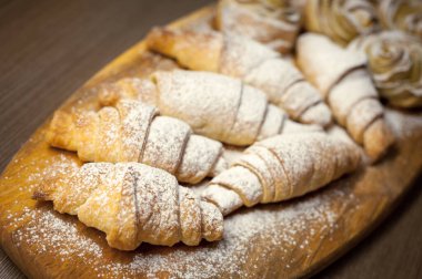 Lezzetli kruvasanlardan ve elmalı pastalardan oluşan bir kafenin ahşap tahtasına yakın.