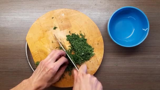 Les mains des hommes coupent le persil avec un couteau de cuisine pointu. La vue du haut . — Video