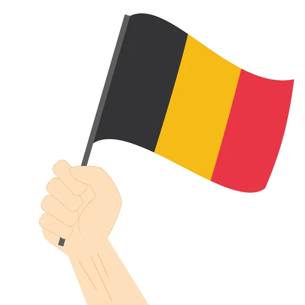 Mão segurando e levantando a bandeira nacional da Bélgica — Vetor de Stock