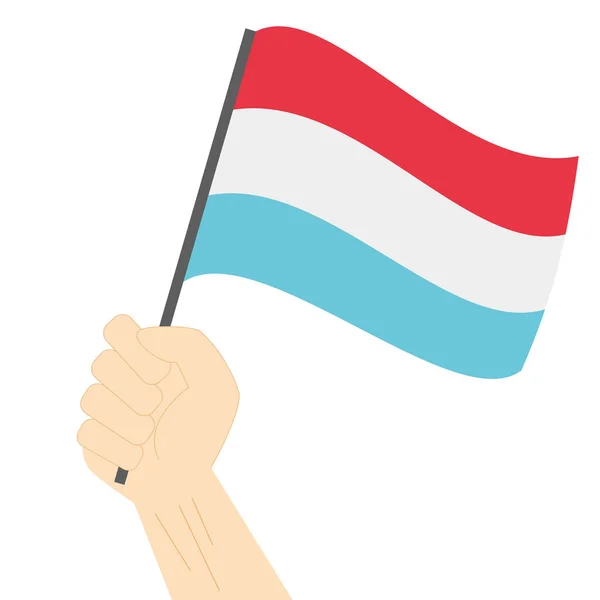 Mão segurando e levantando a bandeira nacional do Luxemburgo — Vetor de Stock