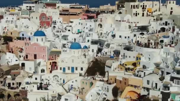 Volando sobre la famosa iglesia con cúpula azul en Oia en la isla de Santorini en Grecia — Vídeos de Stock