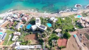 Sahil dünyası sörfçülerin cenneti olarak ünlüdür. Güverte sandalyeleri. Okyanus sörfü ve dalgalar. Taş uçurumlar. Hava görüntüsü. Yunanistan, Girit, Malia.