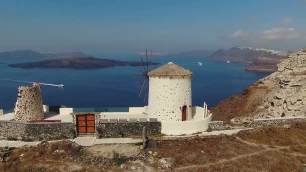 Moinho de vento em Oia, Santorini, Grécia. Vila de Fira na ilha de Santorini, vista aérea, Grécia — Vídeo de Stock
