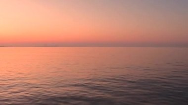 Sahilde Güzel Günbatımı. Gün batımında Baltık Denizi Koyu 'nun güzel manzarası ufukta bulutsuz gökyüzü, uzakta turuncu gölgeler ve huzurlu bir deniz.