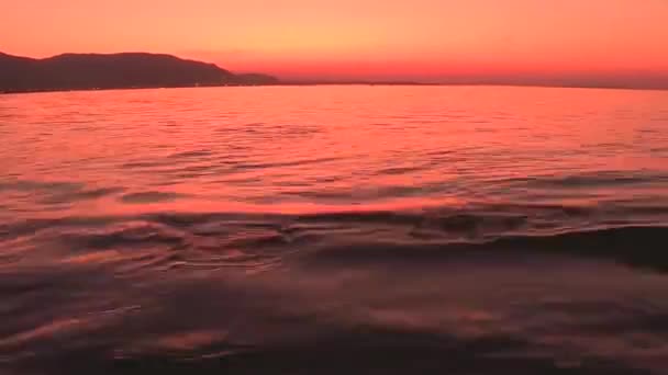 Νωρίς το πρωί ανατολή σε μια αμμόλοφο στον ωκεανό στη Φλώριδα.Όμορφη θέα του κόλπου της Βαλτικής Θάλασσας το ηλιοβασίλεμα, ανέφελους ουρανούς στον ορίζοντα, πορτοκαλί αποχρώσεις στην απόσταση και μια ειρηνική θάλασσα — Αρχείο Βίντεο