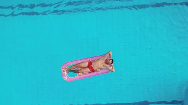 Luftaufnahme eines Mannes, der auf einer aufblasbaren Matratze schwimmt und sich entspannt. — Stockvideo