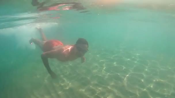 Lassú mozgás nézet: ember ugrik a tengerbe a napsugarak világító neki — Stock videók