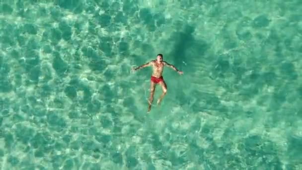 Imágenes de aviones no tripulados por encima de nadador macho flotando en agua azul del mar. Mar Verde — Vídeos de Stock