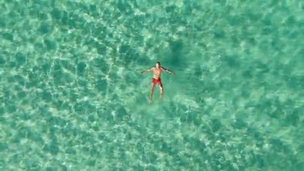 Filmagem de drones acima do nadador masculino flutuando na água do mar azul. Mar Verde — Vídeo de Stock