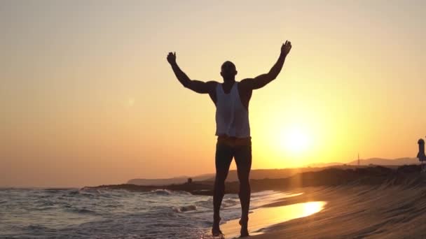 En man Crossfit utbildning på en strand gör Star Jumps hoppa Jacks. — Stockvideo