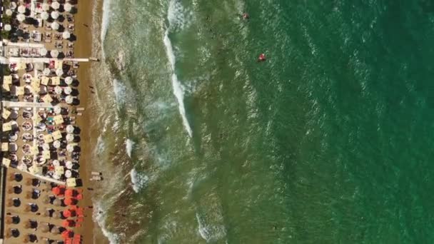Vista aérea superior, voando acima da praia de areia de Azure As pessoas estão tomando banho de sol em toalhas e brincando em água verde . — Vídeo de Stock