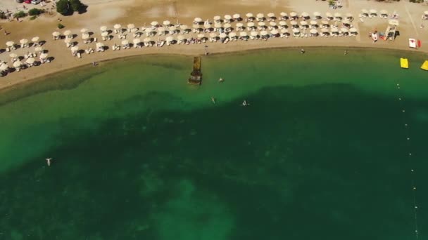 Top aerial view, flying above the sandy beach of Azure People are sunbathing on towels and playing in green water. — Stock Video