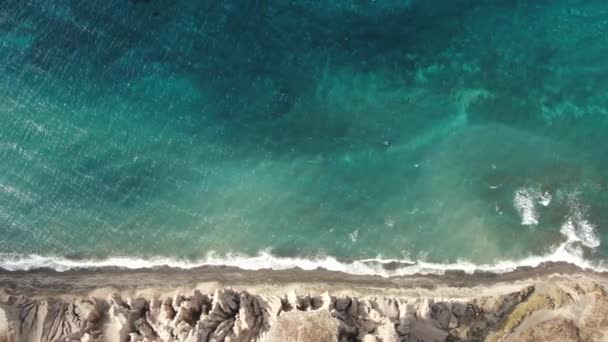 自然のままの熱帯砂のビーチの海岸で破壊されたターコイズブルーの海の波のトップダウンの空中写真サントリーニ — ストック動画