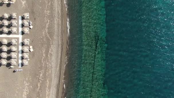 Playa con sombrillas y tumbonas en la orilla del mar Turquesa, Grecia Santorini — Vídeo de stock