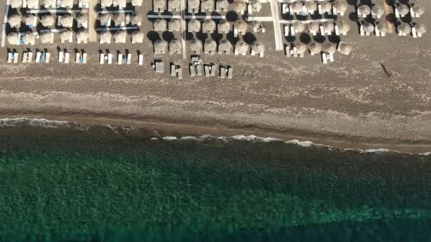 Strand mit Sonnenschirmen und Liegen am Ufer des türkisfarbenen Meeres, Griechenland Santorini — Stockvideo