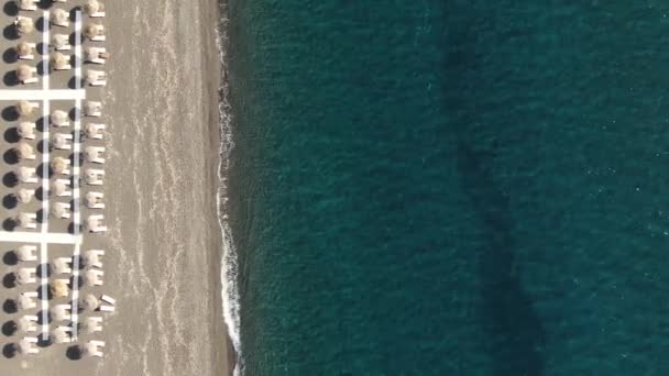 Strand esernyőkkel és napozóágyakkal a Türkiz-tenger partján, Görögország Santorini — Stock videók