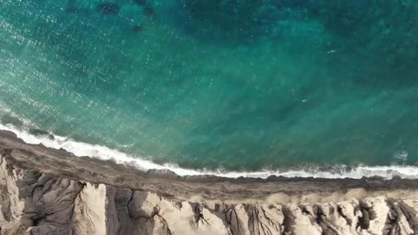 Високогірний вигляд бірюзових блакитних океанічних хвиль, що розбиваються об берег незайманого тропічного піщаного пляжу Санторіні. — стокове відео