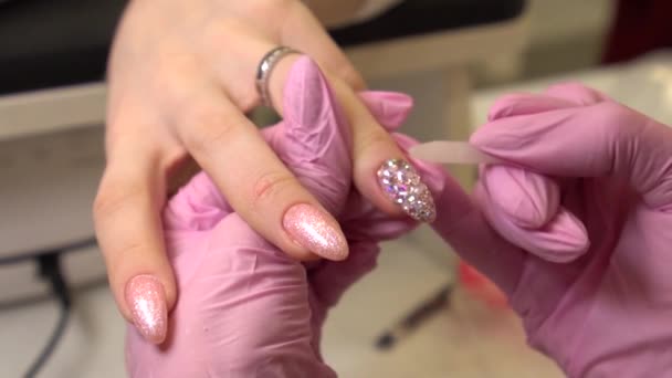 Макро знімок з манікюристом, який прикріплює стрази до розписаних жіночих нігтів, макіяжу та нігтів, крупним планом наносить лак для нігтів — стокове відео
