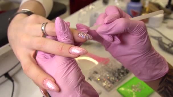 Macro shot con manicure che attacca strass alle unghie dipinte, trucco e unghie, primo piano di applicazione dello smalto — Video Stock