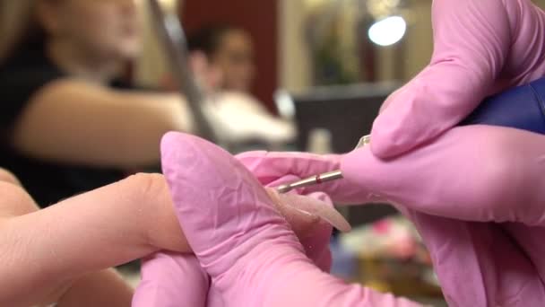 Primer plano de manicura de hardware en un salón de belleza. Manicurista está aplicando taladro de lima de uñas eléctrica para cortar cutículas en dedos femeninos — Vídeo de stock