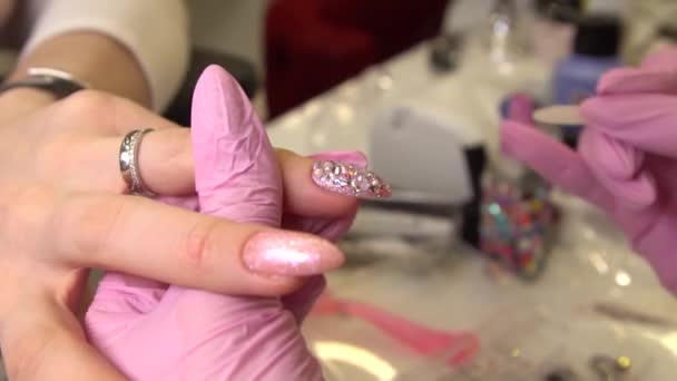 Macro shot con manicure che attacca strass alle unghie dipinte, trucco e unghie, primo piano di applicazione dello smalto — Video Stock