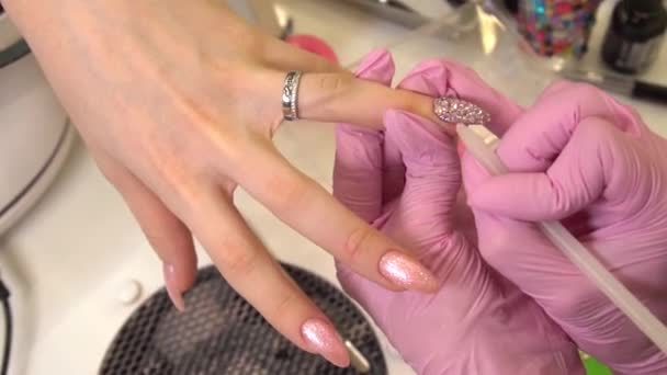 Macro tiro com manicure que cola strass para as unhas mulheres pintadas, maquiagem e unhas, close-up de aplicação de esmalte — Vídeo de Stock