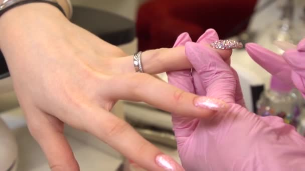 Macro con manicura que se pega pedrería a las uñas pintadas, maquillaje y uñas, primer plano de la aplicación de esmalte de uñas — Vídeo de stock