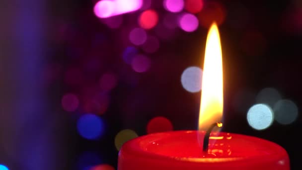 Brennende Kerze auf dem Hintergrund der Silvestergirlande, schnell flackernd. — Stockvideo